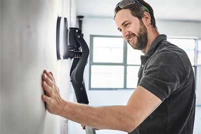 Krāsotājs slīpē sienu ar Festool kāta slīpmašīnu Planex