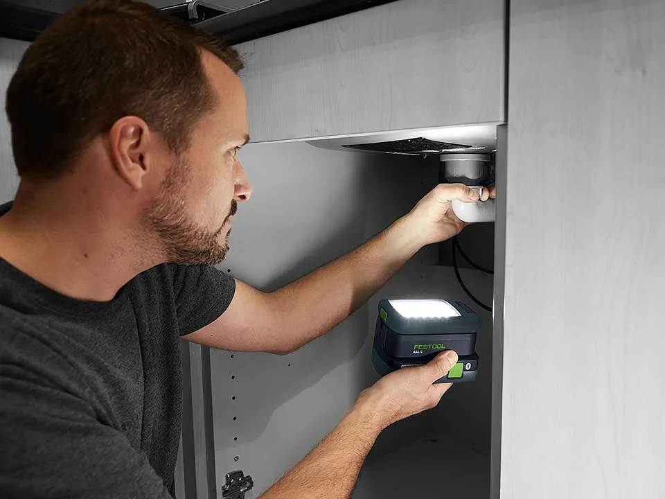 Vīrietis izgaismo izlietnes savienojumu ar SYSLITE KAL 2